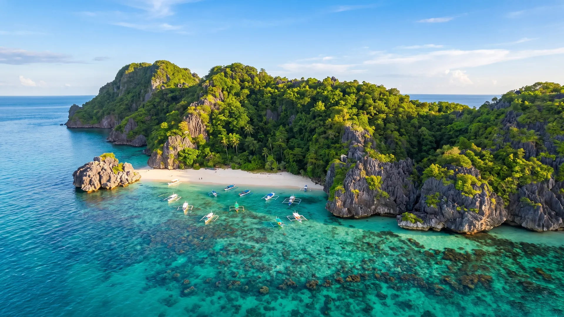 Aerial view of Matukad Island with Filipino outrigger boats moored on turquoise water, Camarines Sur