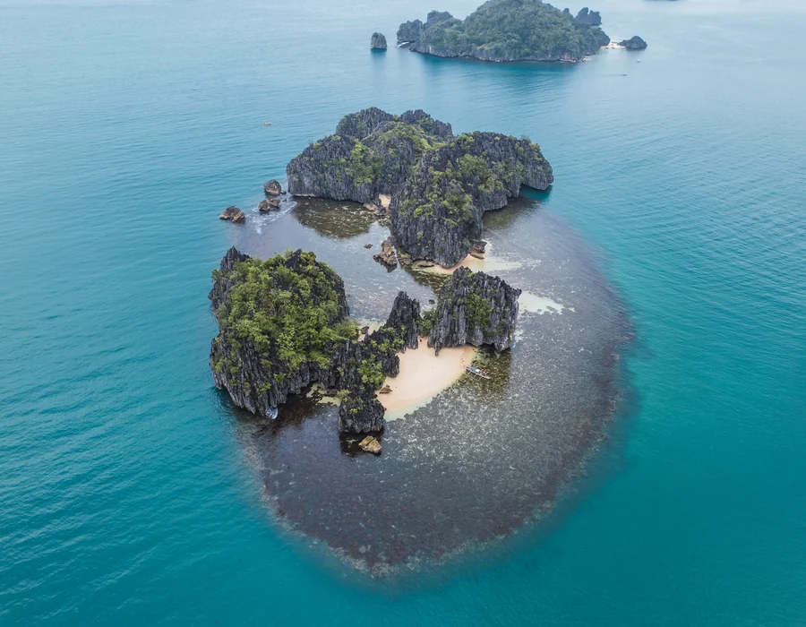 Aerial view of a round island surrounded by turquoise water in Caramoan, Camarines Sur