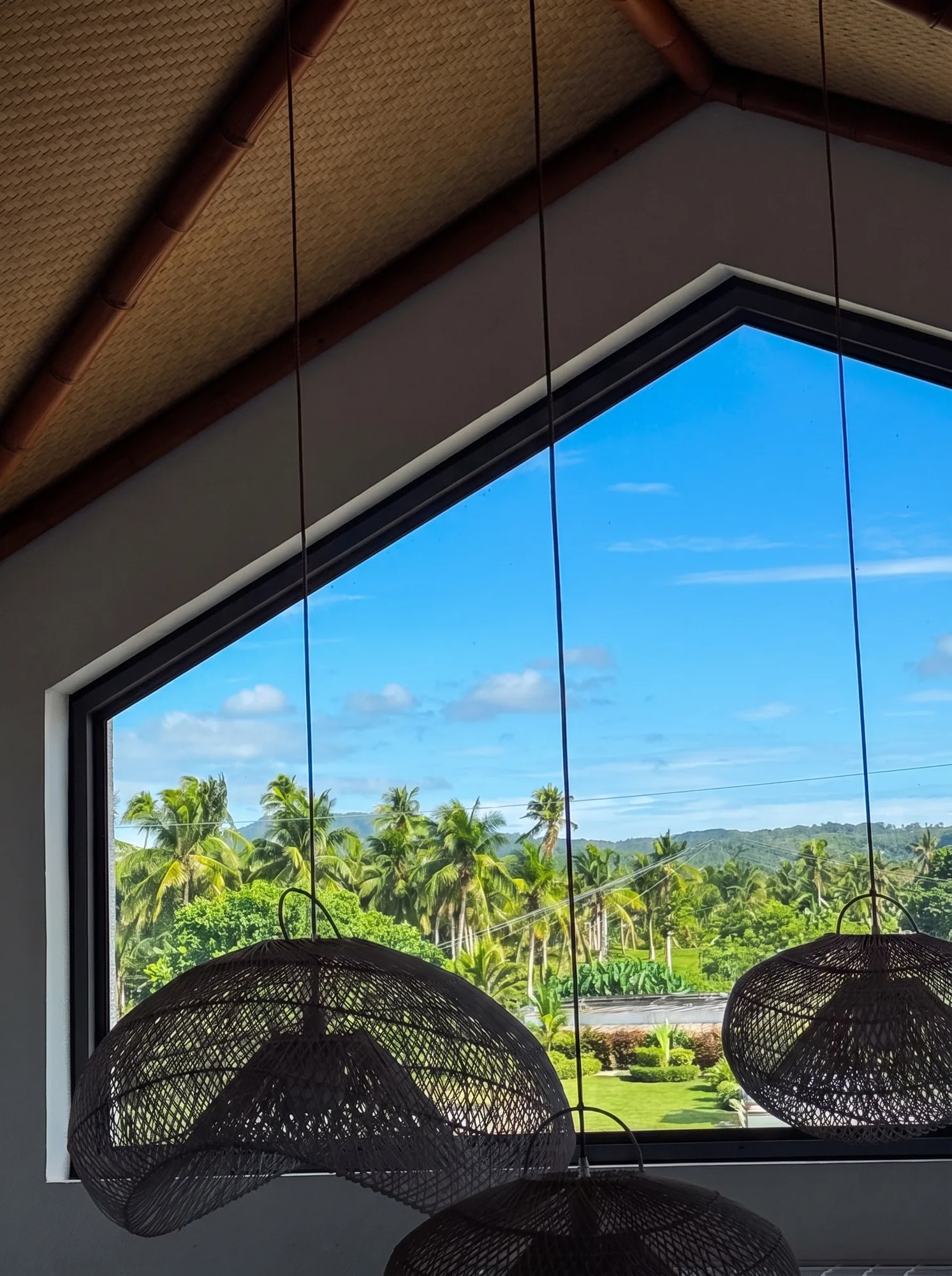 Interior de una villa eco con ventanal de suelo a techo y sillones colgantes