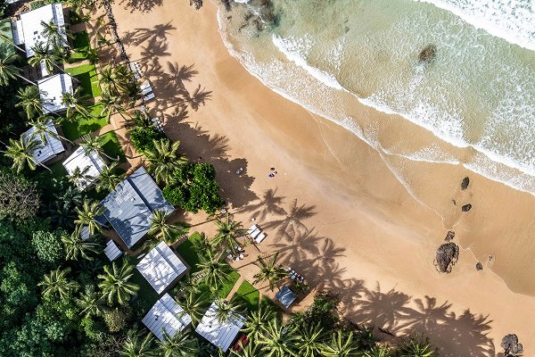 Vista aérea de un resort de playa rodeado de vegetación tropical, ideal para representar turismo sostenible y vivienda en destinos costeros.