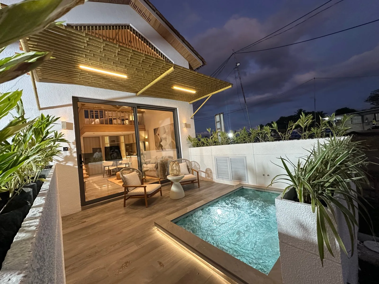 Terraza exterior de una eco villa de San Fernando al anochecer, con la piscina privada iluminada