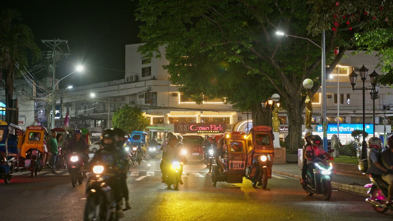 Triciclos y motos circulando de noche por el centro de Naga, en Camarines Sur